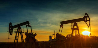 Oil pumpjacks silhouetted at sunset on a rural field