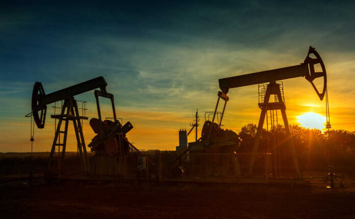 Two,Working,Oil,Pumps,Silhouette,Against,Sunset Oil pumpjacks silhouetted at sunset on a rural field
