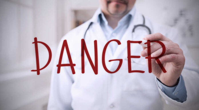 Doctor writing danger on transparent screen