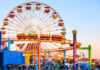 Colorful amusement park scene featuring a ferris wheel and roller coaster at sunset