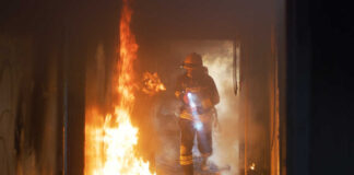 Firefighter with flashlight walking through a burning hallway