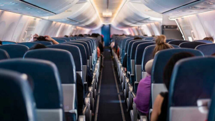 shutterstock_2292032849 Airplane interior with passengers seated mid-flight.