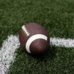 VIDEO: Touchdown, Then Tragedy — Crowd Stunned Silent A brown football resting on green artificial turf near a white line