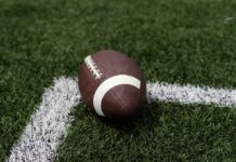 VIDEO: Touchdown, Then Tragedy — Crowd Stunned Silent A brown football resting on green artificial turf near a white line