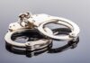 Close-up of metallic handcuffs on a reflective surface