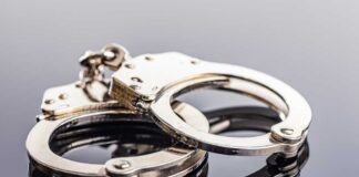 Close-up of metallic handcuffs on a reflective surface