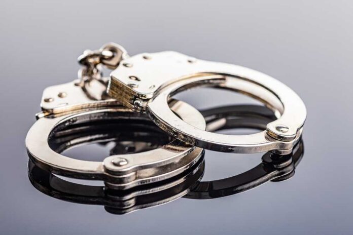 Shiny,Metal,Handcuffs,On,The,Mirror,Table. Close-up of metallic handcuffs on a reflective surface