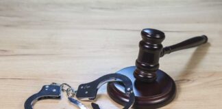 Gavel and handcuffs on wooden table