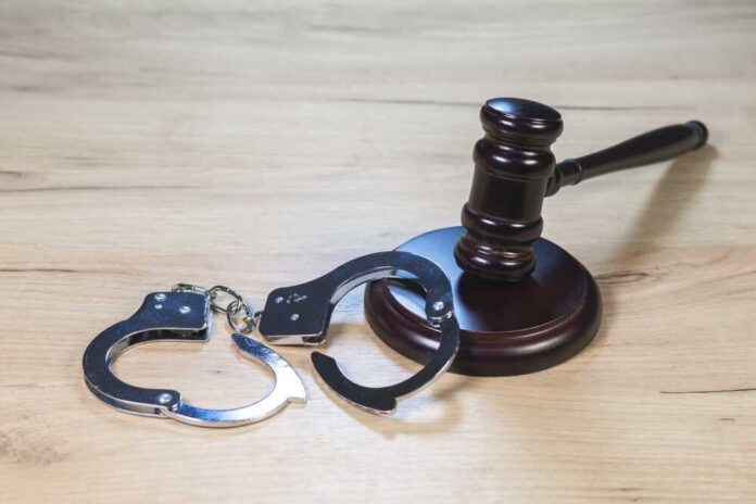 Gavel and handcuffs on wooden table