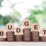 Budget Alarm: Red Ink Explodes Stacks of coins with wooden discs spelling budget