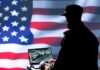 Federal Exodus Warning Stuns D.C. Silhouette of a person using a laptop before a large US flag