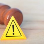 Judges Clash Over $20B Green War Yellow warning triangle with exclamation mark beside a wooden gavel