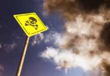 VIDEO: Gold Pit Turns Mass Grave Yellow skull and crossbones warning sign against smoky sky