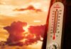 Thermometer displaying high temperature against a sunset background