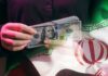 Economic D-Day: Trump Targets Iran’s Wallet A person holding a stack of US hundred-dollar bills in front of the Iranian flag