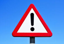 Rescue Mission Hit — Sailors Killed A triangular warning sign with an exclamation mark against a blue sky