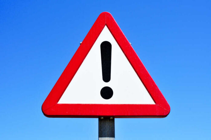A,Triangular,Traffic,Sign,With,An,Exclamation,Mark,Against,The A triangular warning sign with an exclamation mark against a blue sky