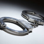 Horror Mask Menace Nabbed Close-up of metallic handcuffs on a light surface
