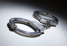 Horror Mask Menace Nabbed Close-up of metallic handcuffs on a light surface