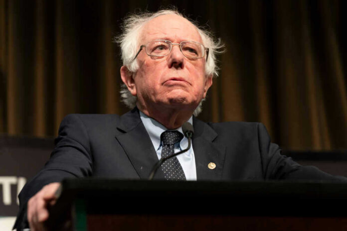 shutterstock_1360787486 Bernie Sanders at a podium in a suit and tie