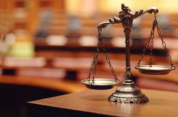 shutterstock_140867215 Scales of justice in an empty courtroom.