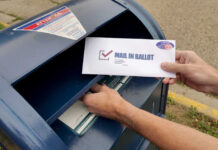Mail-Ballot Crackdown Hits Legal Wall? Hands mailing a ballot envelope into a blue mailbox