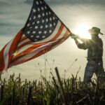 Person holding an American flag against a sunset backdrop
