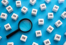 Six-Figure Jobs Sit Empty – Warning Issued Magnifying glass among cubes labeled job on blue background