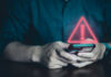 Person holding phone with warning symbol displayed.