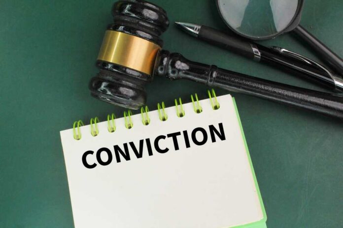 Pen,,Judge's,Gavel,And,A,Book,With,The,Word,Conviction. A gavel resting on a notepad with the word 'CONVICTION' written on it