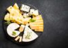 Cheese platter with assorted slices and wedges on a black slate board