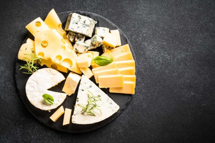 Cheese,Platter,With,Craft,Cheese,Assortment,At,Black,Background. Cheese platter with assorted slices and wedges on a black slate board