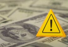 NEWS ALERT: $120 Warning Issued A yellow warning sign placed on a background of dollar bills