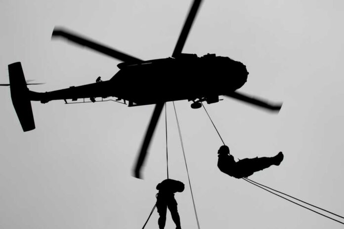 U.s.,Army,Air,Assault,Students,Practice,Rappelling,Out,Of,A Silhouette of a helicopter with two individuals being lowered by ropes