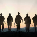 Pentagon Orders Annual T Tests — NEW DETAILS Five armed soldiers silhouetted against sunset background.