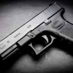 Black Glock 19 pistol on a dark surface.