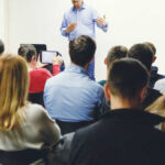 100,000 Jobs? Automaker Drops the Hammer Man giving a lecture to a group of people.