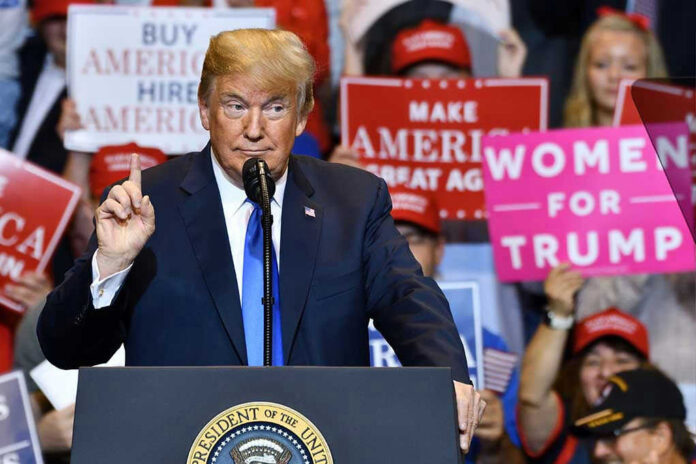 1148319797-1 Donald Trump speaks at a rally with Bill Kenney in the crowd holding signs