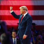 Trump Dangles Fraud Bounty Donald Trump raises a fist on stage before a large U.S. flag