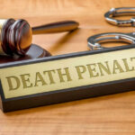 Double Dose, Inmate Lives Gavel handcuffs and death penalty sign on table