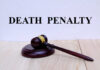 Firing Squad Return Stuns Nation A wooden gavel resting on a block with the words 'DEATH PENALTY' in bold above it