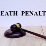 Firing Squad Return Stuns Nation A wooden gavel resting on a block with the words 'DEATH PENALTY' in bold above it