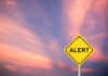 Drone Attacks Trigger U.S. Pullback Yellow alert sign against a colorful sunset sky