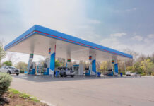 A modern gas station with fuel pumps and parked vehicles
