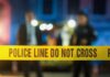Police tape at a night scene with blurred officers in the background