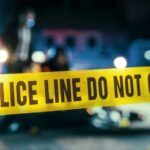 Home Invasion Horror Police line caution tape at a crime scene with blurred figures in the background
