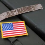 Marine Arrest Sparks Fury Military patches including a US Marines insignia and an American flag on a green surface