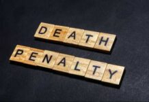 Wooden letter tiles spelling DEATH PENALTY on a dark background