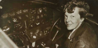 Amelia Earhart seated in an airplane cockpit, looking toward the camera