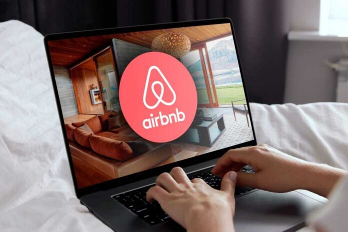 Hands using a laptop with Airbnb app on screen